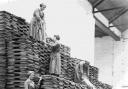 One of the pictures shows women workers stacking oil cakes at an oil and cake factory in Lancashire in 1918