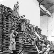 One of the pictures shows women workers stacking oil cakes at an oil and cake factory in Lancashire in 1918