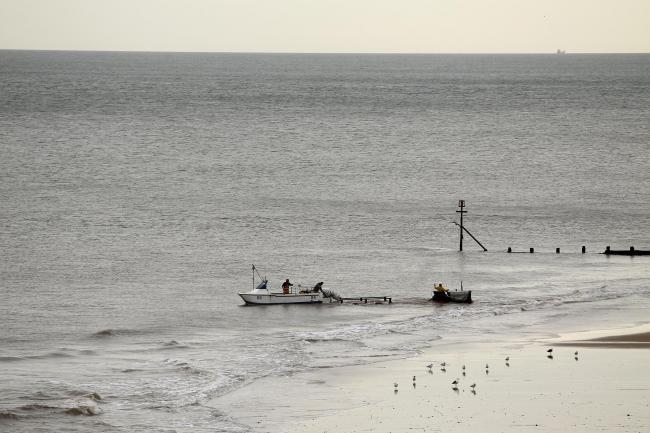 A fishing boat is towed in on the beach in the seaside town of Cromer on the north Norfolk coast