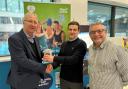 Cllr David Molyneux MBE (left) and Cllr Chris Ready (right) present a Fitbit Sense 2 health tracker to Be Well member Christian Worthington