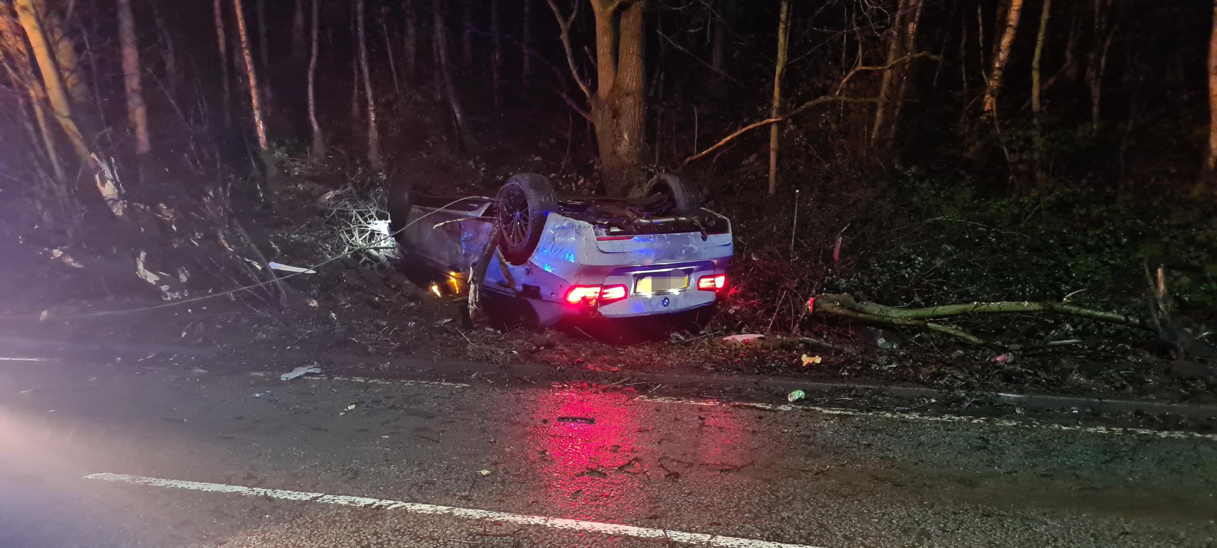 A grey BMW collided with a tree causing a branch to fall onto the road