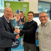 Cllr David Molyneux MBE (left) and Cllr Chris Ready (right) present a Fitbit Sense 2 health tracker to Be Well member Christian Worthington